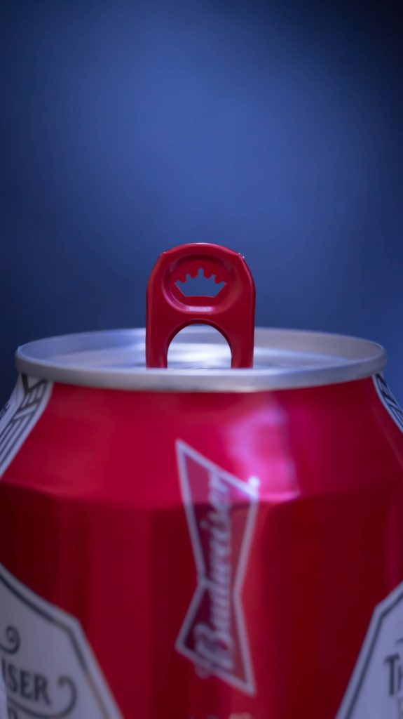 Close-up of Budweiser beer can with red crown pull tab on deep blue background wallpaper