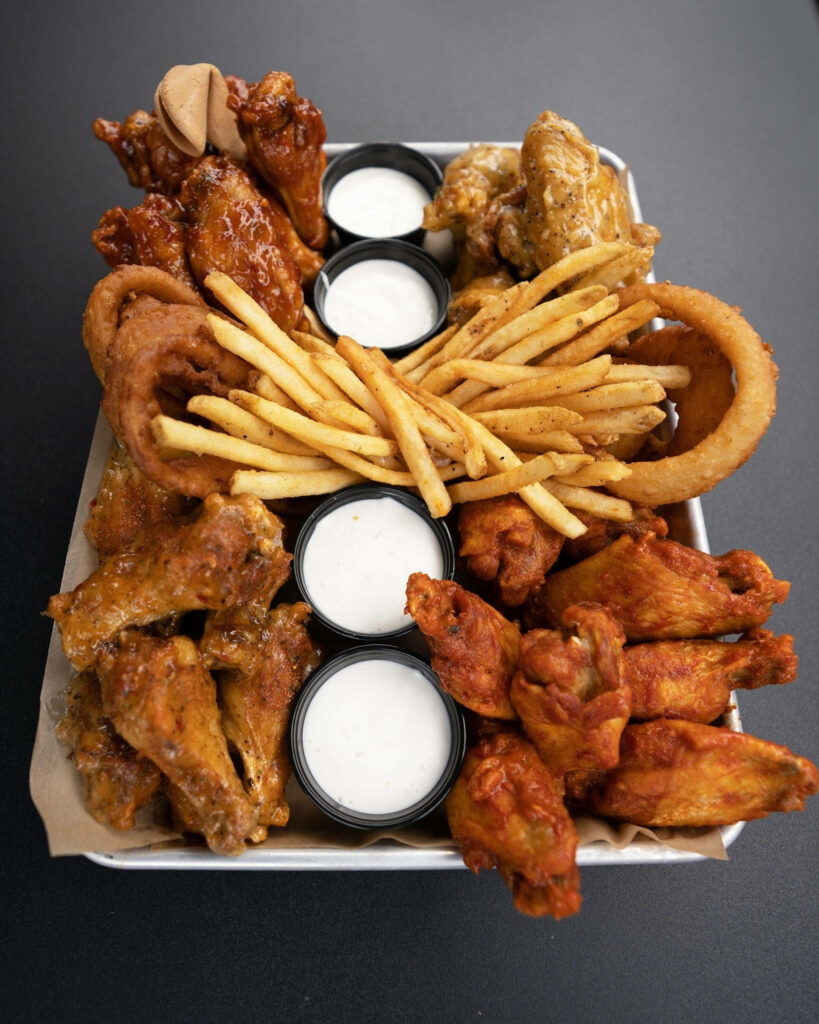 Overhead view of Buffalo Wild Wings platter with crispy wings onion rings fries and dipping sauces Wallpaper