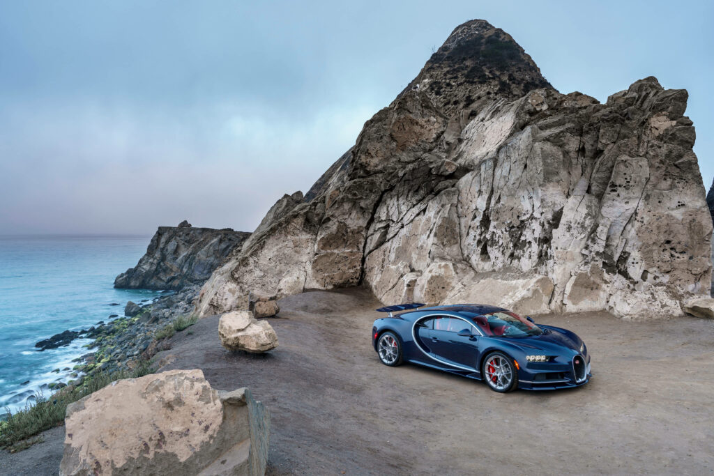 Bugatti Chiron deep blue on rocky seaside cliff with misty ocean high performance supercar wallpaper
