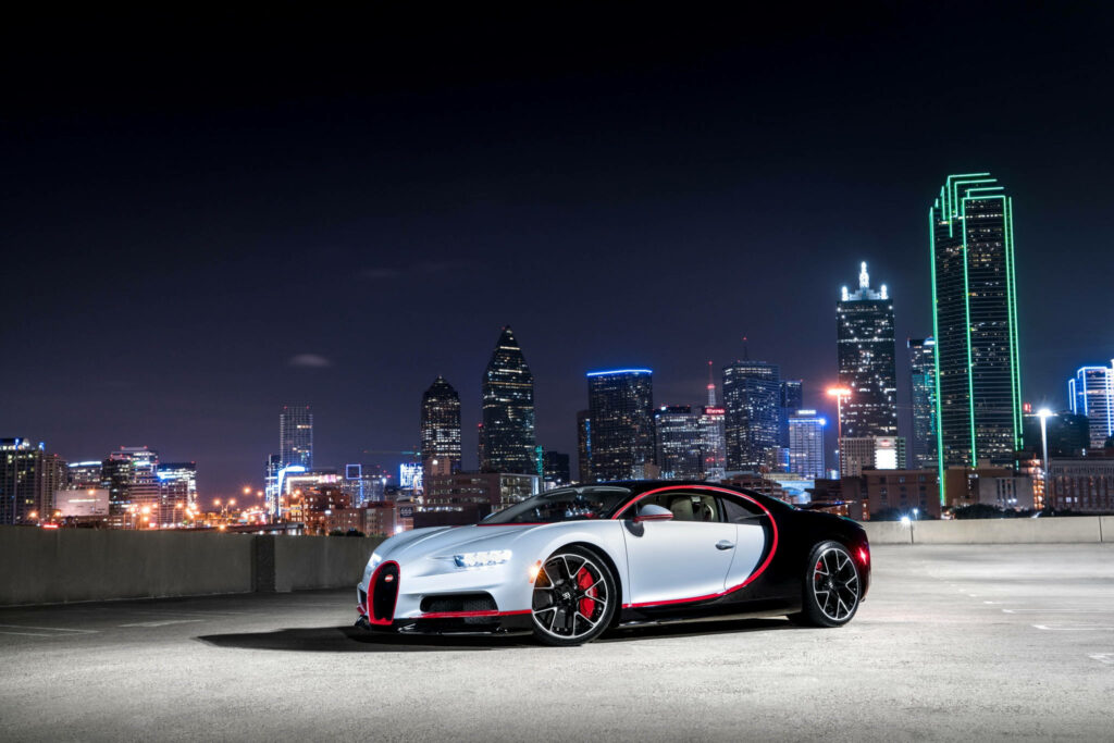 Bugatti Chiron sports car on rooftop at night with vibrant city skyline background wallpaper
