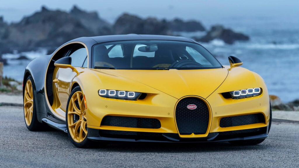 Yellow and black Bugatti Chiron parked by scenic coastline showcasing sleek design and luxury Wallpaper
