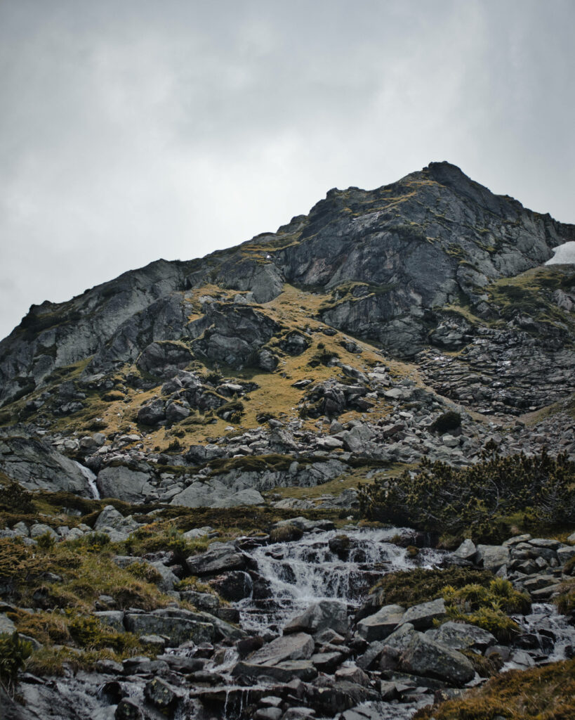 Bulgaria Stone Mountain rocky peak with waterfall greenery and cloudy sky wallpaper background
