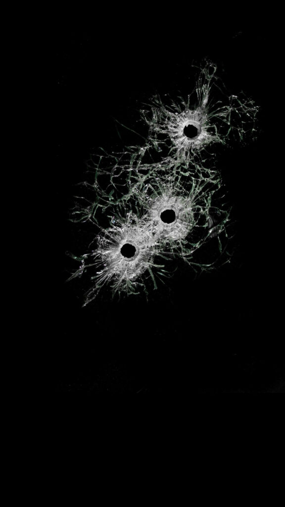 Bullet holes on broken glass wallpaper with shattered patterns on solid black background