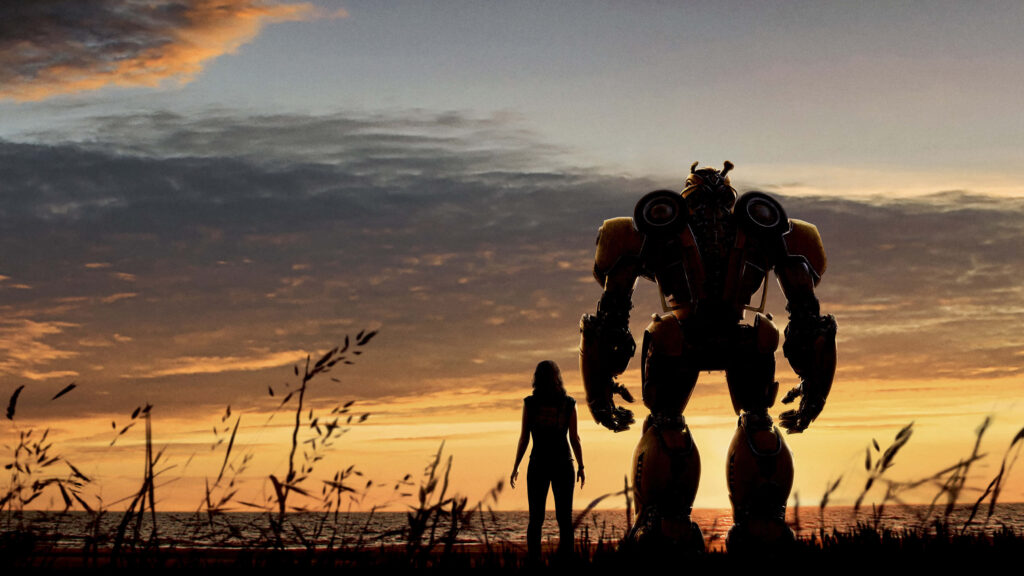 Bumblebee robot with human companion on sunset beach dramatic sky friendship wallpaper background