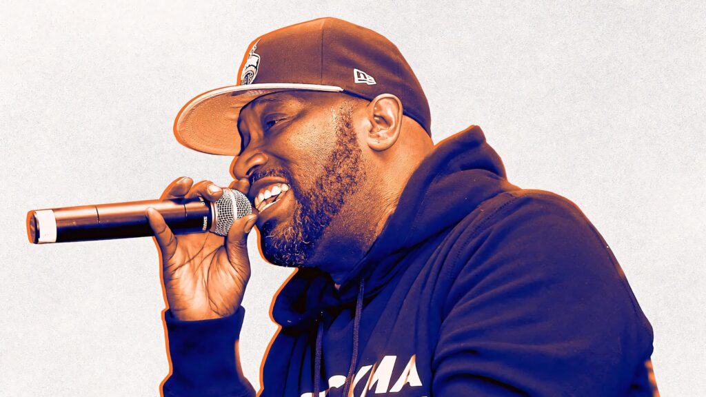 Bun B rapping live wearing cap and hoodie vibrant warm tones hip hop performance wallpaper background