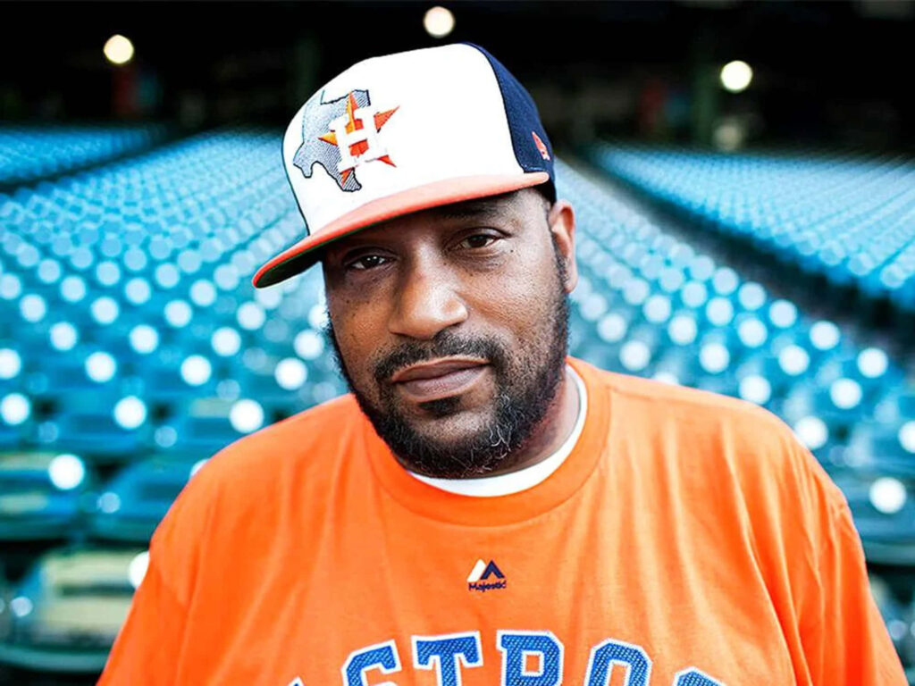Bun B rapper in Houston Astros cap and shirt standing in vibrant empty stadium seats wallpaper