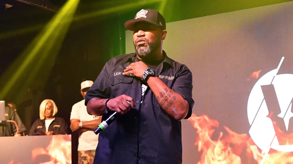 Bun B performing live in black shirt and cap with fiery stage lights hip hop wallpaper background
