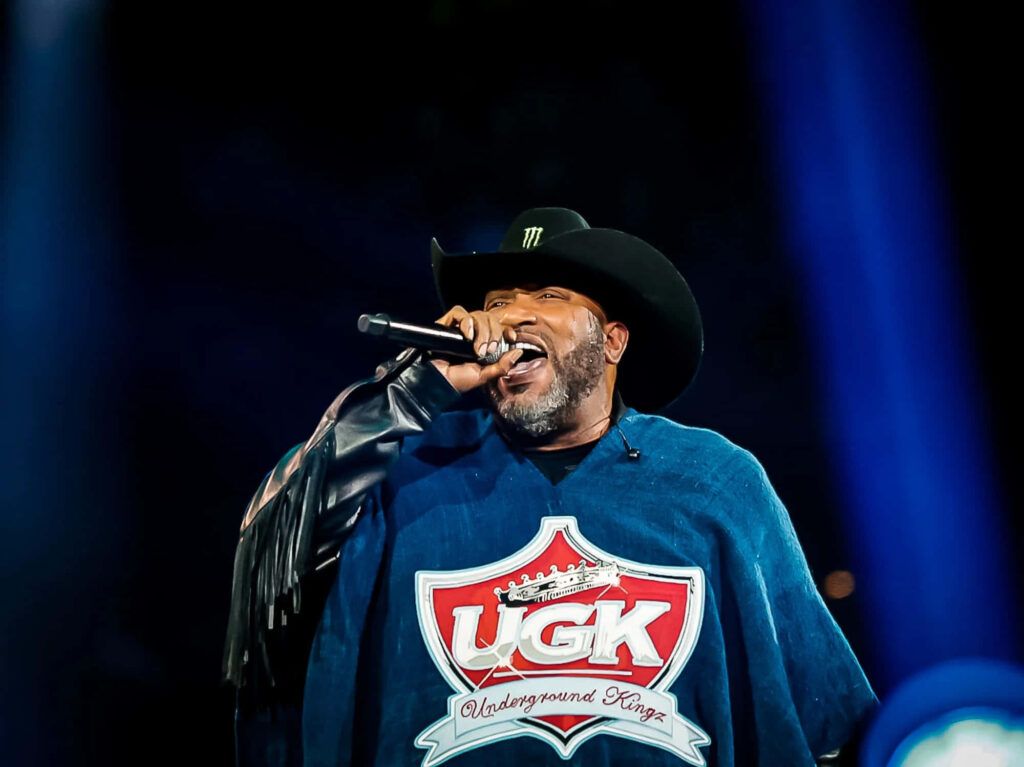 Bun B live performance wearing cowboy hat and UGK poncho vibrant Southern hip hop stage lighting Wallpaper
