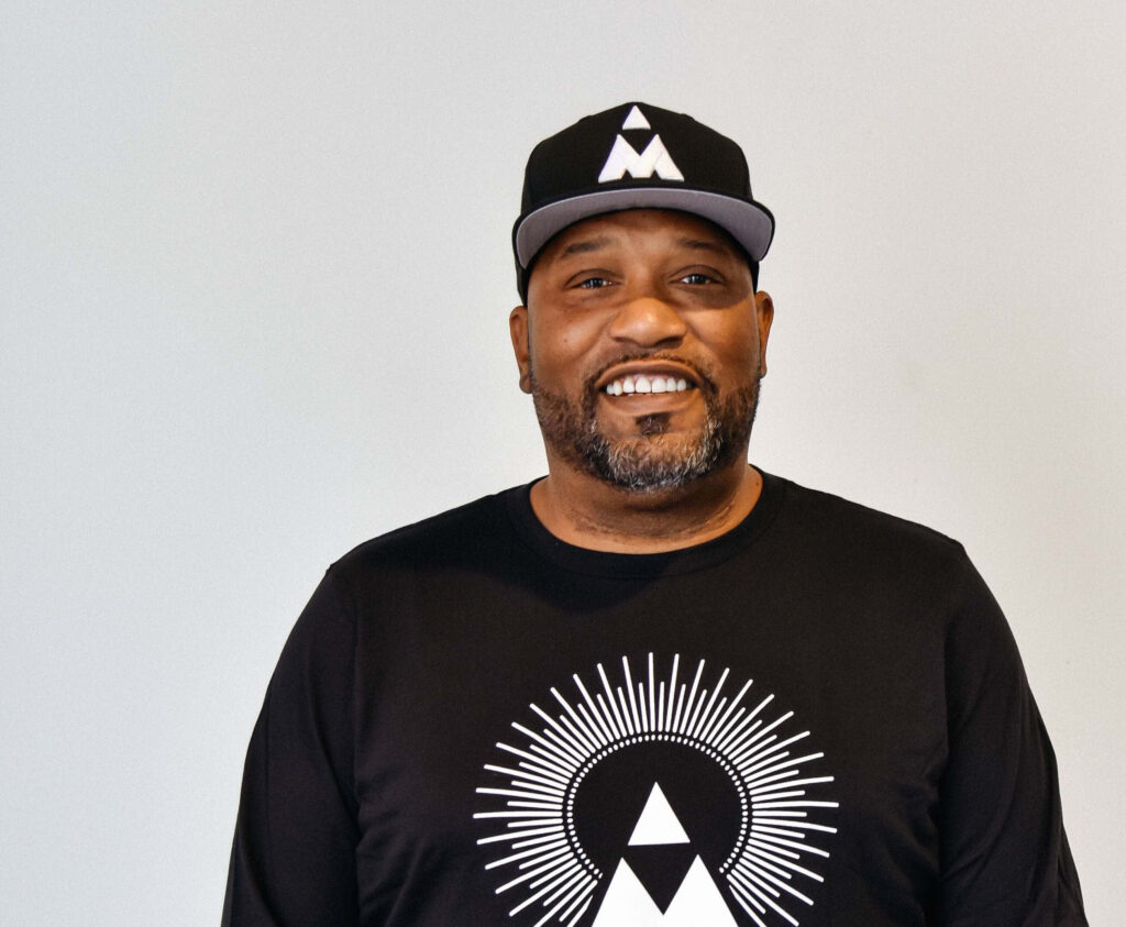 Bun B rapper in black geometric shirt and cap standing against plain light modern background Wallpaper