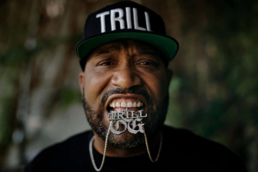 Bun B rapper wearing TRILL cap and biting TRILL OG chain with confident hip-hop style wallpaper