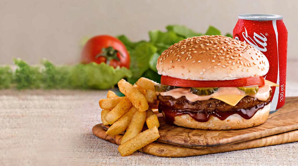 Burger King cheeseburger with fresh toppings crispy fries and cold Coca Cola on wooden board Wallpaper