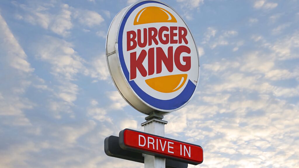 Burger King logo with red Drive In sign against vivid sky and soft clouds wallpaper background