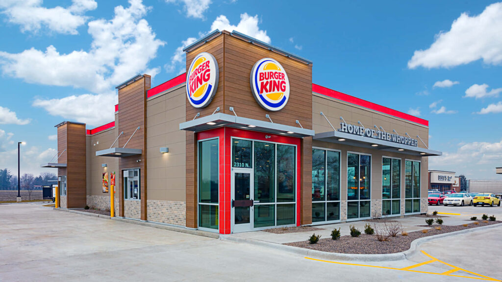 Vibrant Burger King restaurant with iconic logo under bright blue sky with fluffy clouds wallpaper
