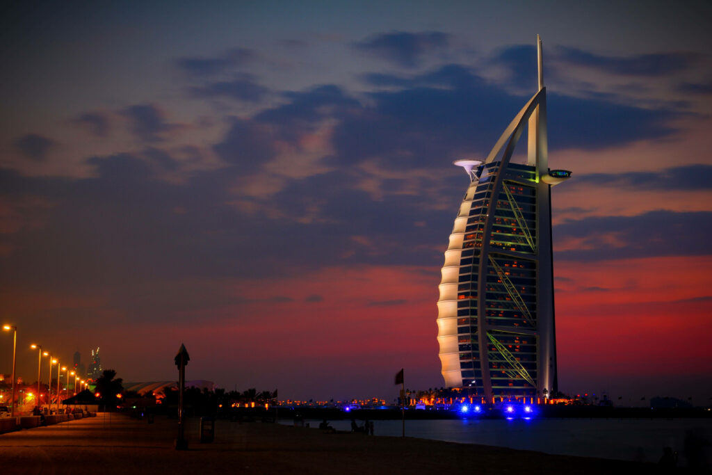 Burj Al Arab illuminated at night with vibrant blues and purples showcasing its sail design Wallpaper