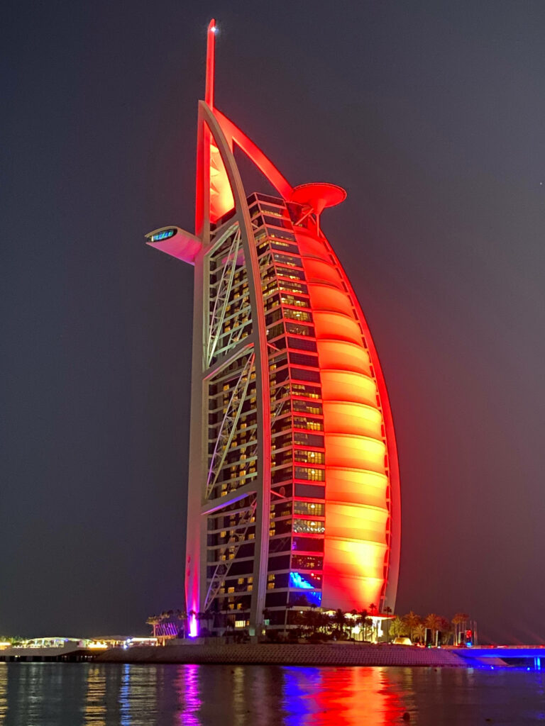 Burj Al Arab Jumeirah illuminated orange at night reflecting on calm water luxury wallpaper background
