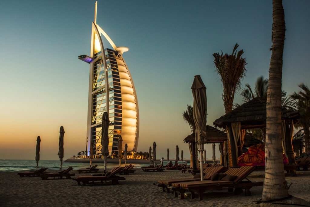 Burj Al Arab at sunset with palm trees and beach deck chairs in warm golden light wallpaper