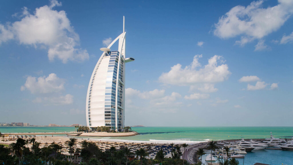 Burj Al Arab Dubai luxury hotel with white sail design against blue sky and turquoise waters wallpaper