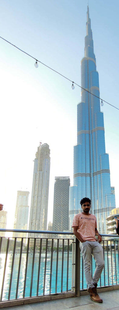Burj Khalifa towering over Dubai cityscape with blue glass skyscrapers under bright daylight Wallpaper