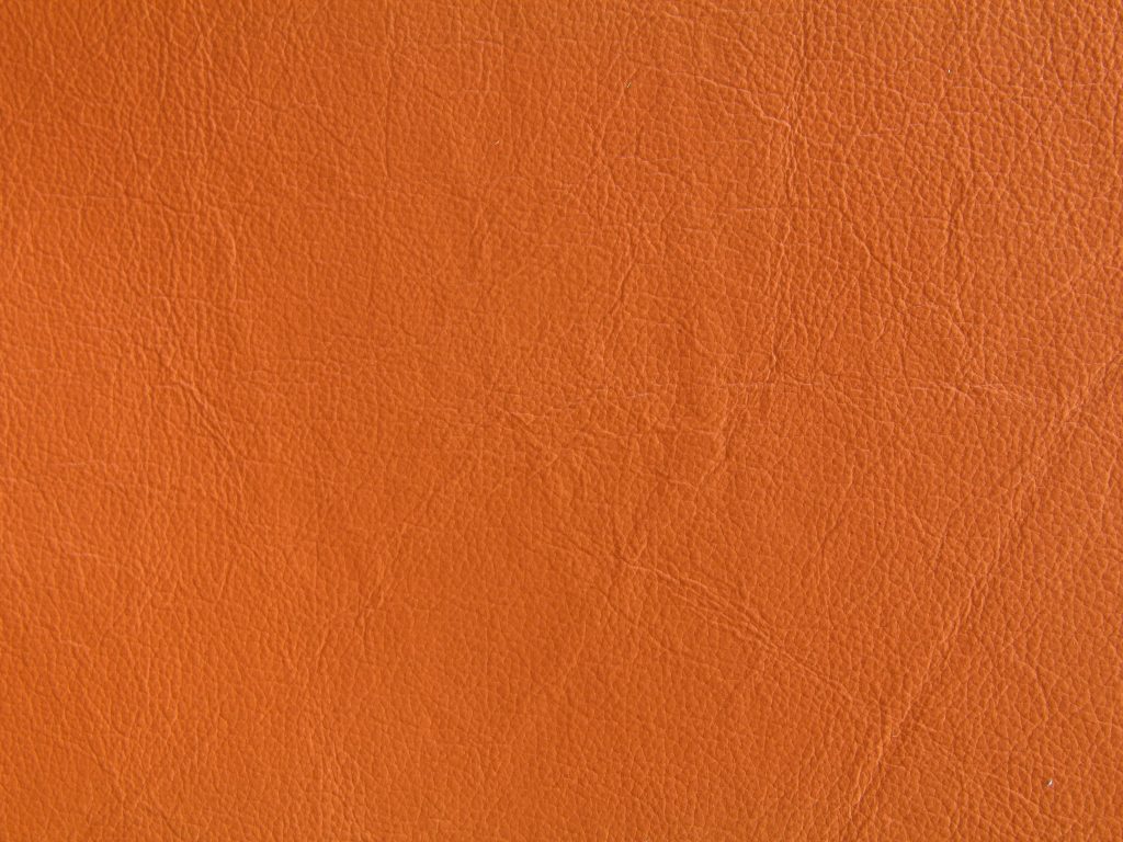 Macro close-up of textured burnt orange leather wallpaper background for modern minimalist screens