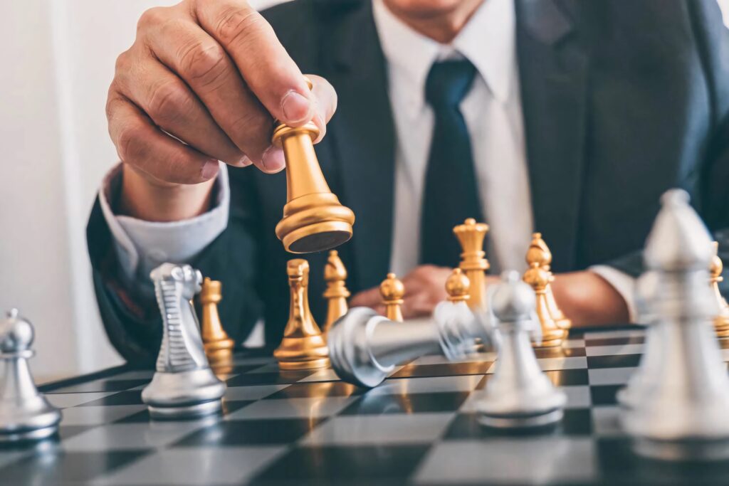 Businessman in suit strategizing over metallic chessboard with gold and silver pieces sharp focus Wallpaper