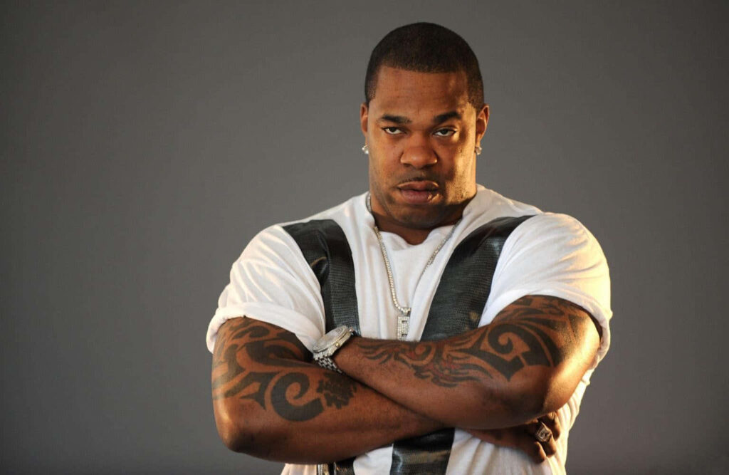 Busta Rhymes with crossed arms and tattoos against gray background iconic hip hop artist wallpaper
