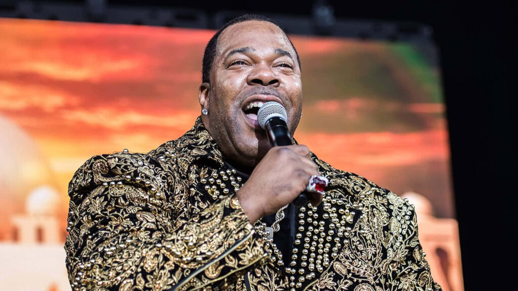 Busta Rhymes live performance in gold black jacket singing vibrant sunset concert background wallpaper