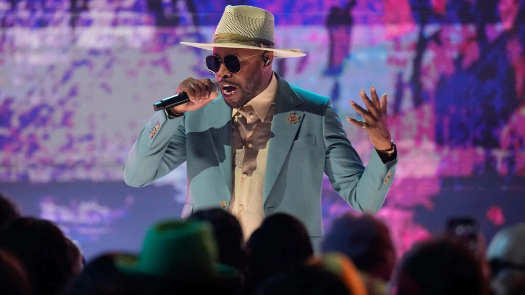 Busta Rhymes live performance in stylish blue suit beige hat sunglasses vibrant abstract background Wallpaper