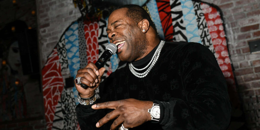 Busta Rhymes performing live with microphone urban graffiti backdrop sparkling jewelry hip hop style Wallpaper