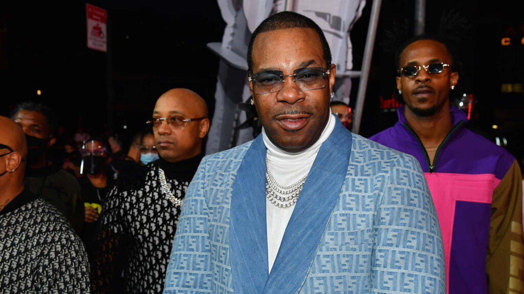 Busta Rhymes in patterned jacket layered chains and tinted glasses at vibrant urban event wallpaper