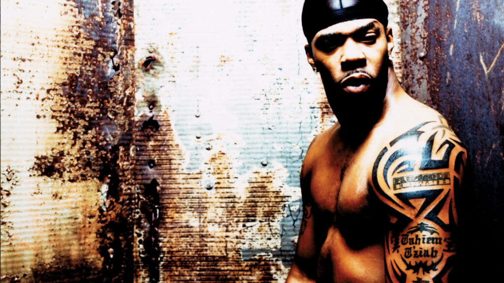 Busta Rhymes muscular pose with bold tattoo urban gritty background dramatic lighting wallpaper