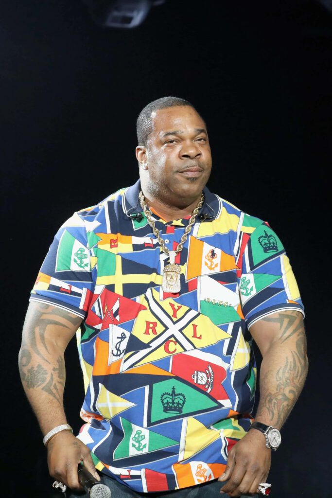 Busta Rhymes on stage in colorful nautical flag outfit with vibrant patterns and dynamic energy Wallpaper