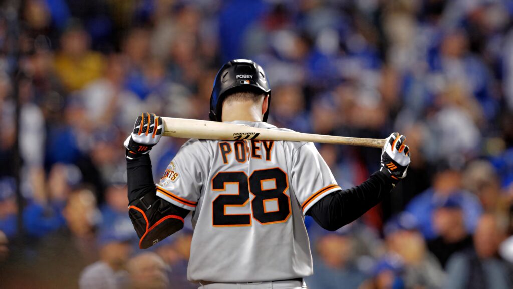 Buster Posey at home plate in Giants jersey number 28 with vibrant stadium crowd background Wallpaper