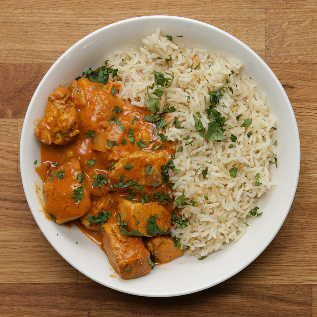 Butter chicken curry with fluffy steamed rice and cilantro on wooden background wallpaper