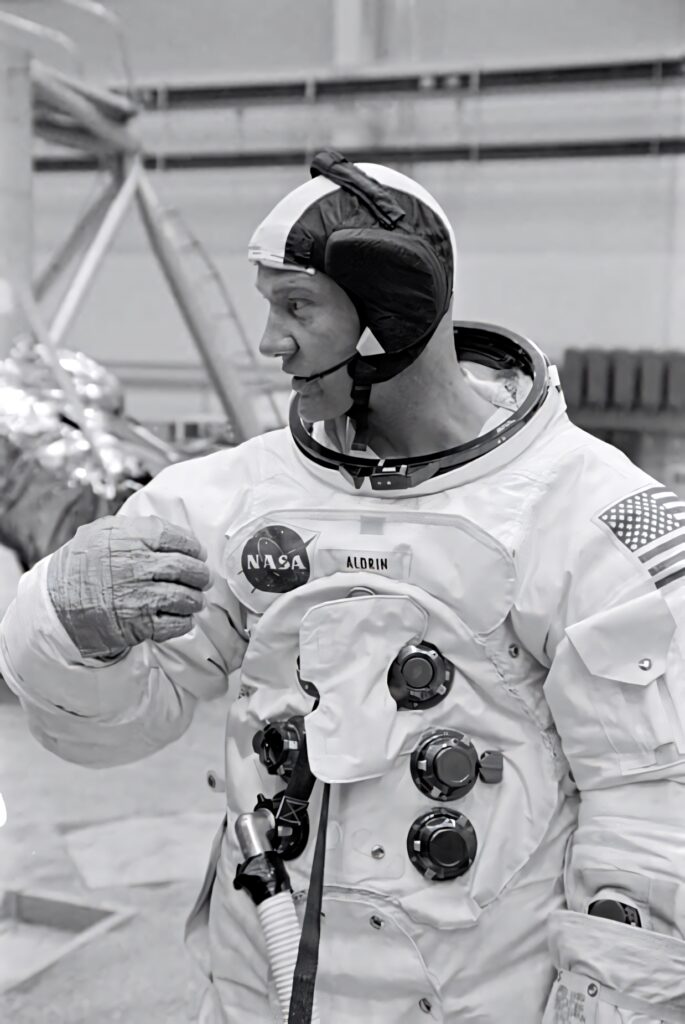 Buzz Aldrin in detailed NASA spacesuit during test showing intricate controls and patches Wallpaper