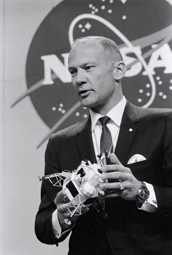 Buzz Aldrin in suit holding detailed Lunar Module model NASA backdrop grayscale historic photo Wallpaper