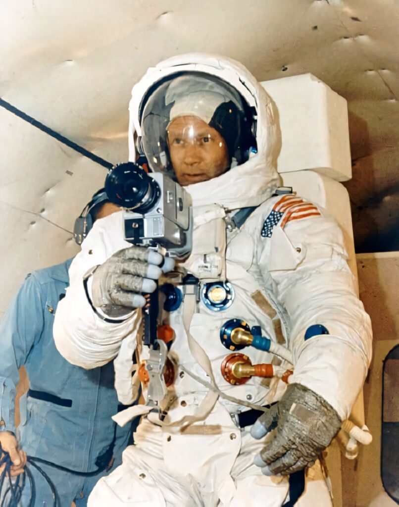 Buzz Aldrin in white NASA spacesuit holding camera with American flag patch historic space photo Wallpaper