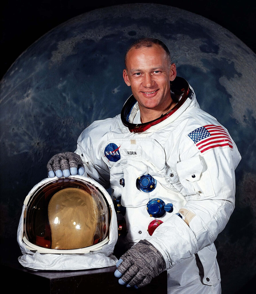 Buzz Aldrin in NASA spacesuit holding helmet with moon backdrop Apollo mission wallpaper
