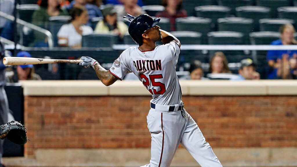 Byron Buxton mid-swing in white uniform baseball action shot vibrant stadium background wallpaper