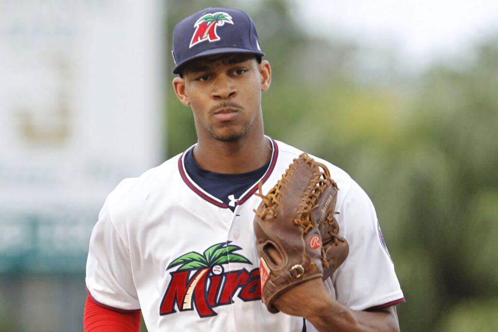 Byron Buxton in white Miracles jersey and cap holding Rawlings mitt ready on baseball field Wallpaper