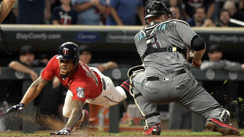 Byron Buxton sliding aggressively into base in Minnesota Twins jersey during intense baseball game Wallpaper