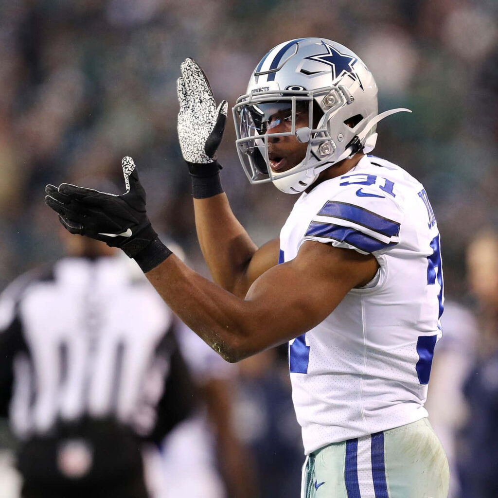 Byron Jones clapping in Dallas Cowboys uniform during intense game with vibrant stadium background Wallpaper