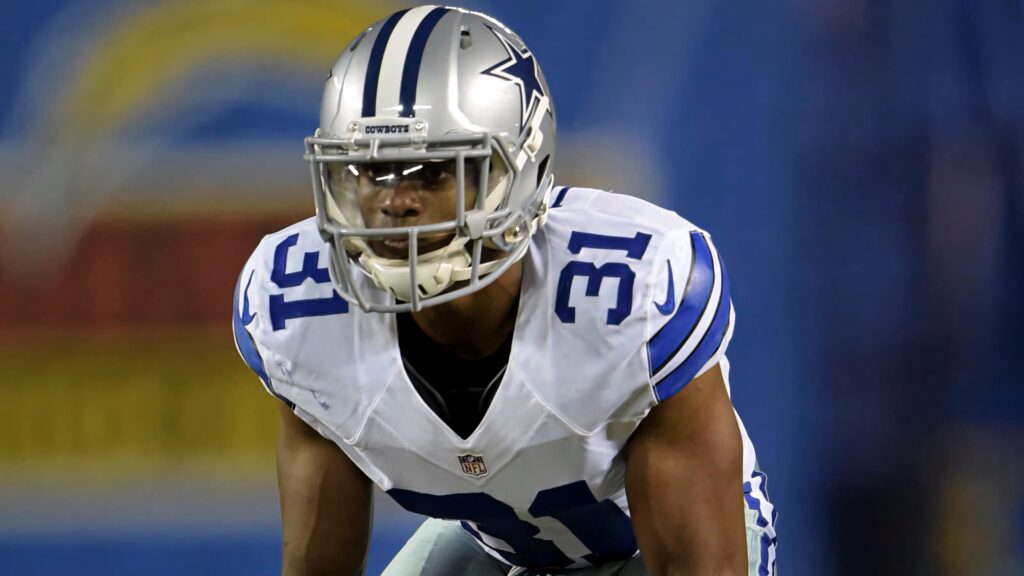 Byron Jones Dallas Cowboys defense intense athletic stance in white blue uniform game background Wallpaper