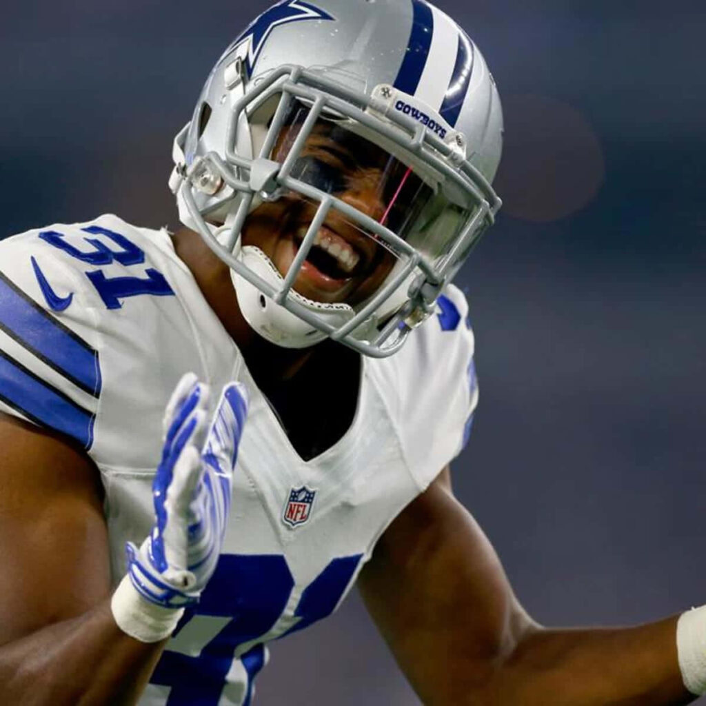 Byron Jones laughing in Dallas Cowboys uniform with helmet during game vibrant stadium backdrop Wallpaper