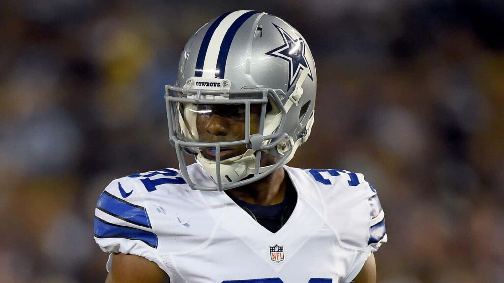Byron Jones in Dallas Cowboys uniform with silver helmet and blue star logo on game field Wallpaper
