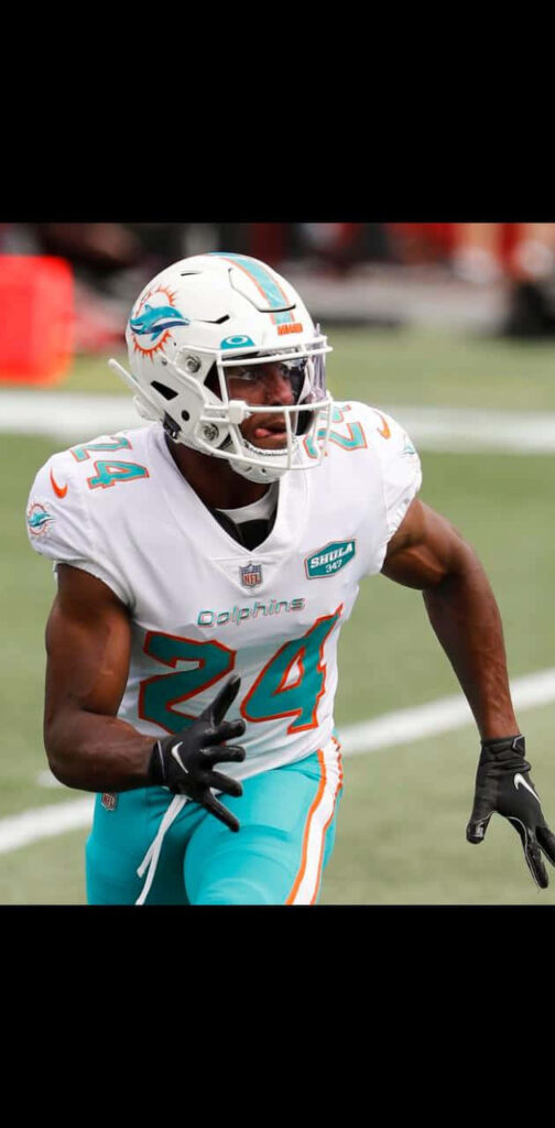 Byron Jones running in Miami Dolphins uniform on field with vibrant colors and blurred stadium background Wallpaper