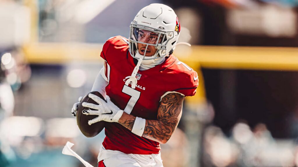 Byron Murphy in red Arizona Cardinals uniform running with football on sunlit field dynamic play Wallpaper
