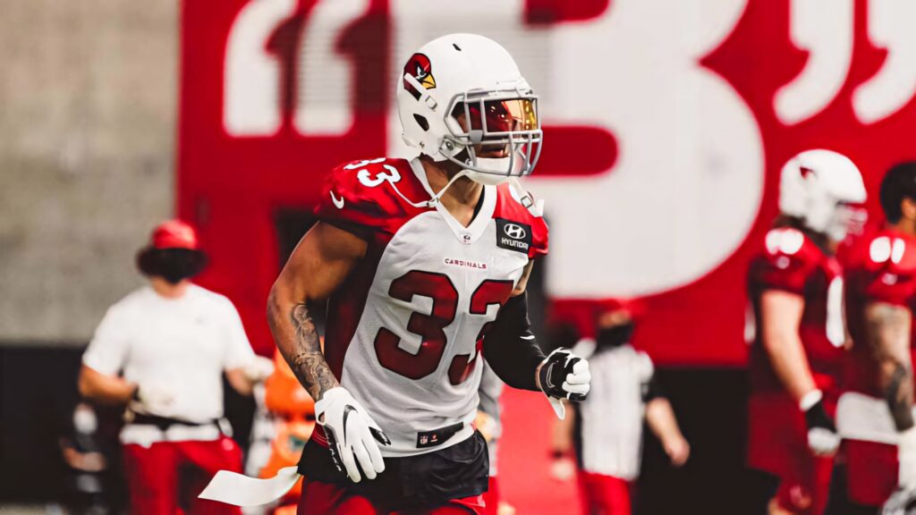Byron Murphy in Arizona Cardinals uniform focused in defensive stance with vibrant stadium backdrop Wallpaper