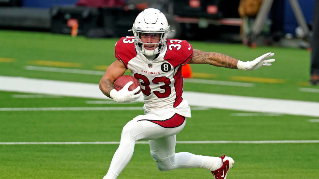 Byron Murphy running with football in Arizona Cardinals red uniform on green field during game Wallpaper