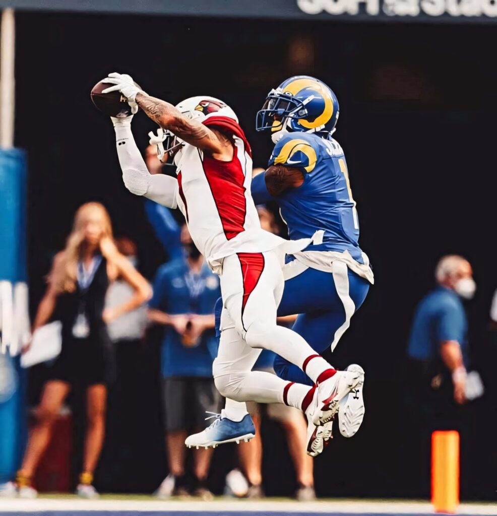 Byron Murphy in red Cardinals uniform leaping mid-air to intercept pass against Rams player Wallpaper