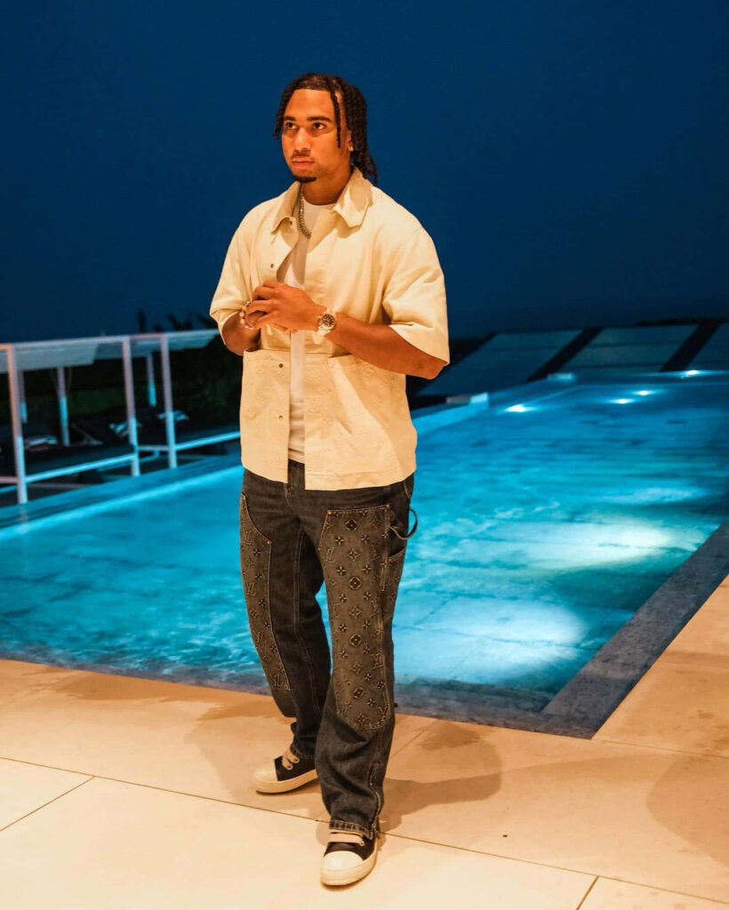 C J Stroud poolside at night in casual light shirt and patterned jeans with blue water lighting Wallpaper